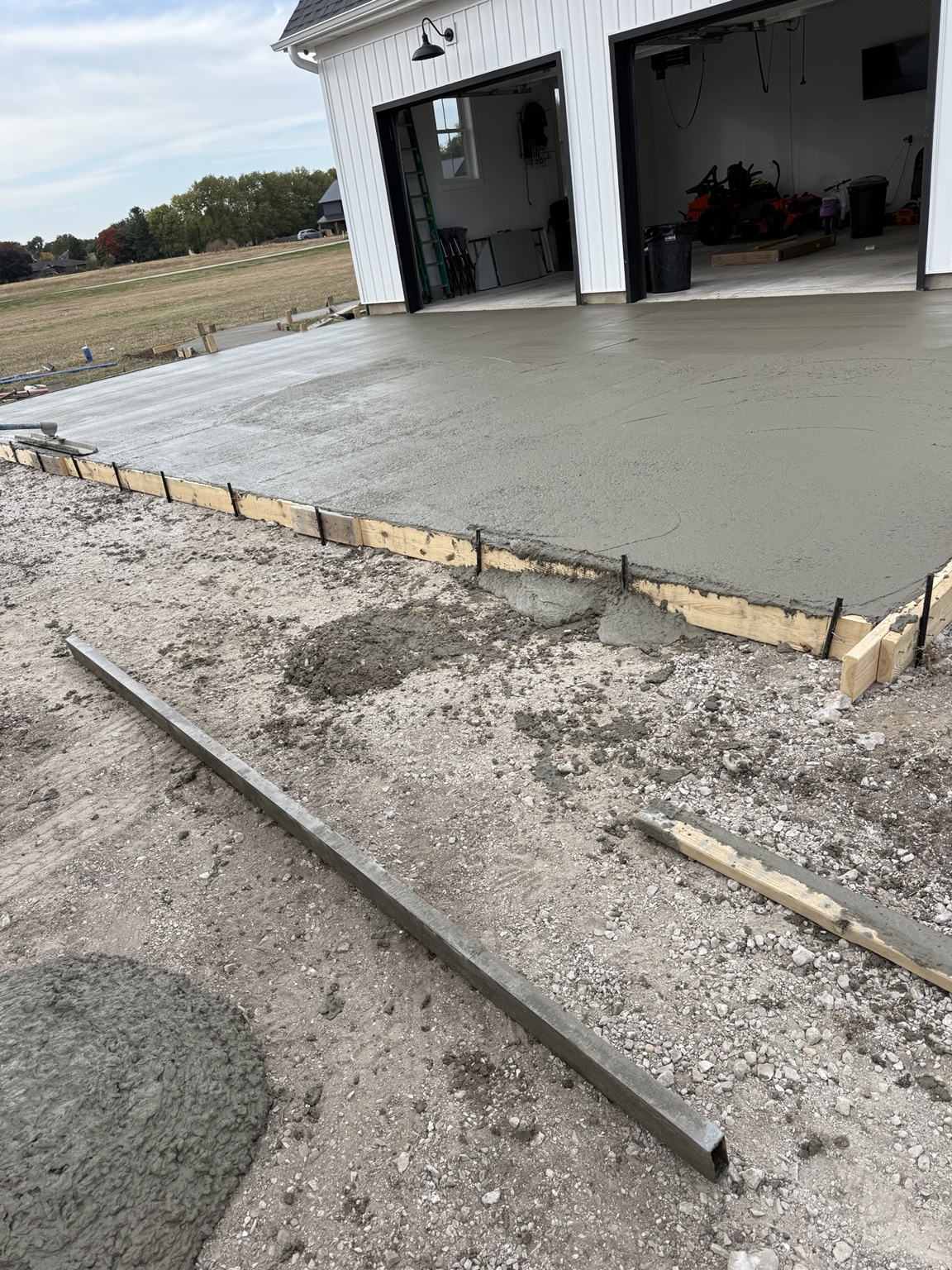 Fresh concrete being finished beside a garage